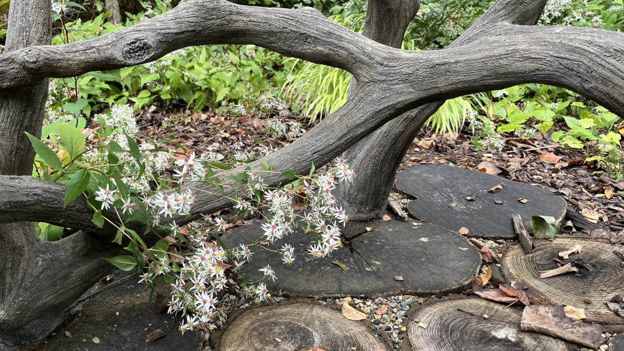 faux bois structure with white aster flowers and a base made of rounds of wood