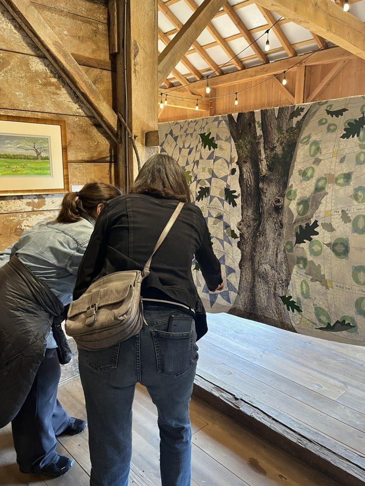 two women admiring the details of a quilt in a gallery